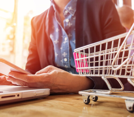 Cropped image of woman inputting card information and key on phone or laptop while shopping online.